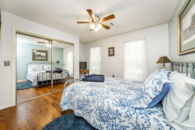 bedroom with ceiling fan, dark hardwood / wood-style flooring, a textured ceiling, and a closet