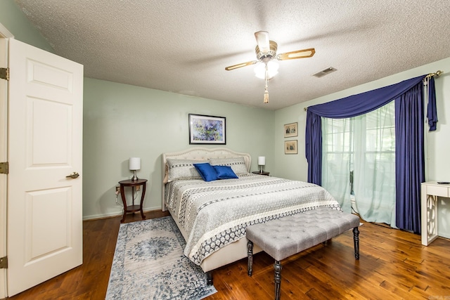 bedroom featuring ceiling fan, dark wood-type flooring, and a textured ceiling