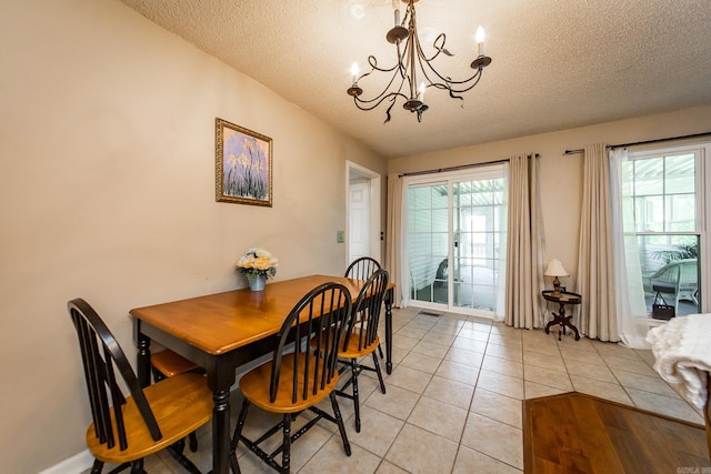 dining area with a textured ceiling, an inviting chandelier, and light tile patterned flooring