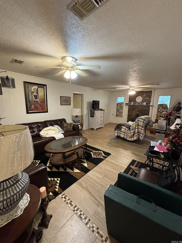 living room featuring ceiling fan, a fireplace, a textured ceiling, and hardwood / wood-style flooring