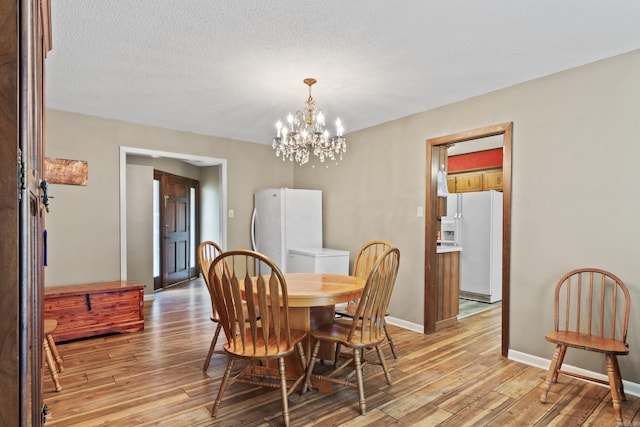 dining space featuring light hardwood / wood-style floors, a textured ceiling, and an inviting chandelier