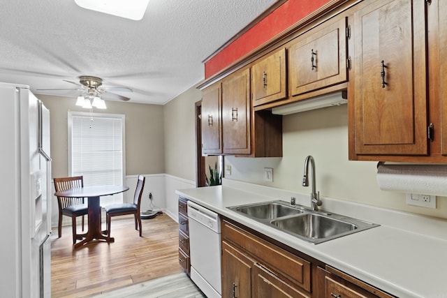 kitchen with a textured ceiling, white appliances, ceiling fan, sink, and light hardwood / wood-style flooring