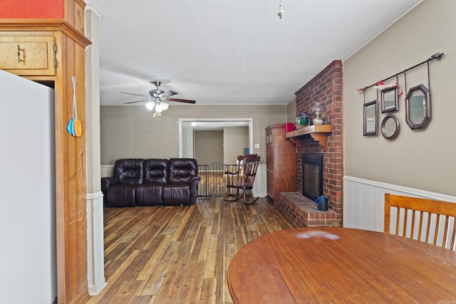 dining space featuring a fireplace, hardwood / wood-style floors, and ceiling fan