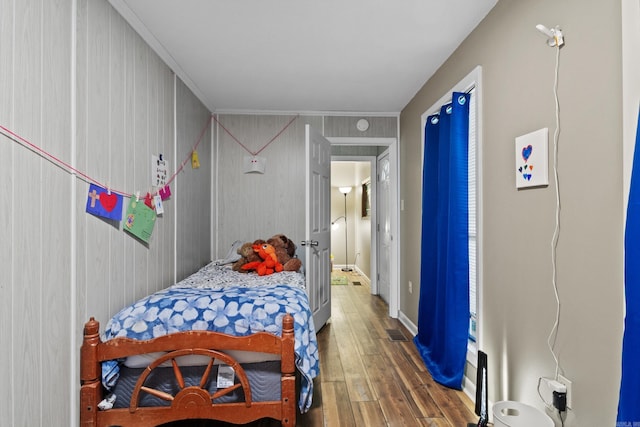 bedroom featuring crown molding, dark wood-type flooring, and wood walls