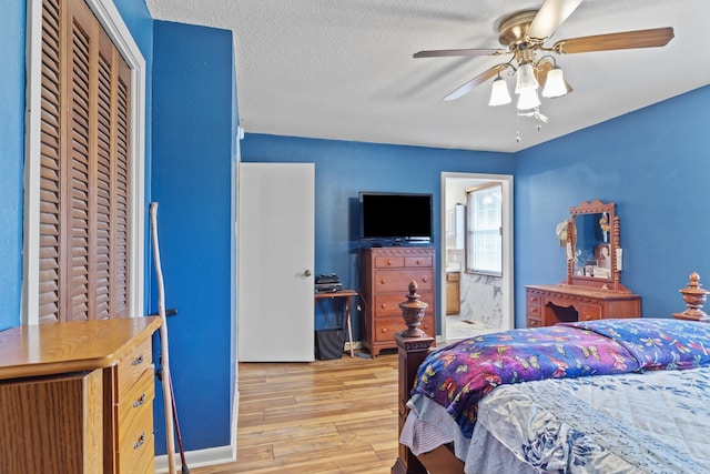 bedroom featuring ensuite bath, a textured ceiling, ceiling fan, light hardwood / wood-style flooring, and a closet