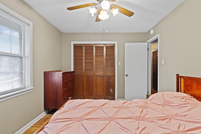 bedroom with multiple windows, hardwood / wood-style floors, a closet, and ceiling fan