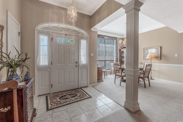 carpeted entrance foyer featuring decorative columns, crown molding, and an inviting chandelier