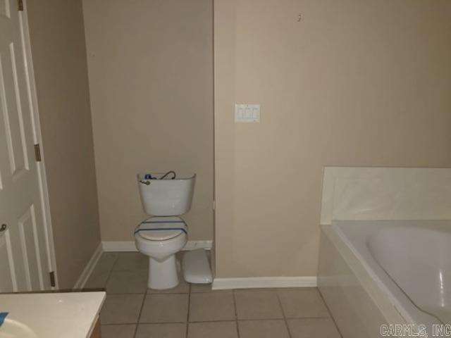 bathroom featuring tile patterned floors, vanity, toilet, and a tub to relax in