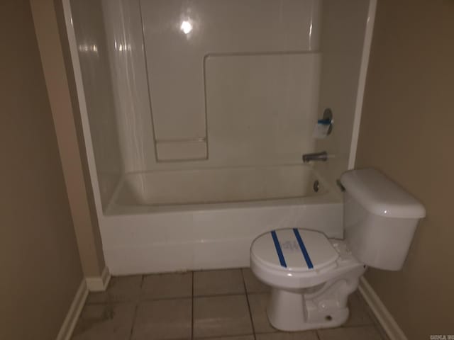 bathroom featuring bathing tub / shower combination, tile patterned flooring, and toilet