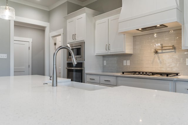 kitchen with custom exhaust hood, white cabinets, hanging light fixtures, decorative backsplash, and appliances with stainless steel finishes