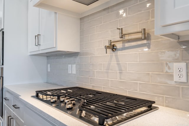 kitchen featuring white cabinets, light stone counters, backsplash, and stainless steel gas cooktop