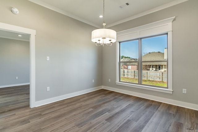 spare room with dark hardwood / wood-style floors, an inviting chandelier, and ornamental molding