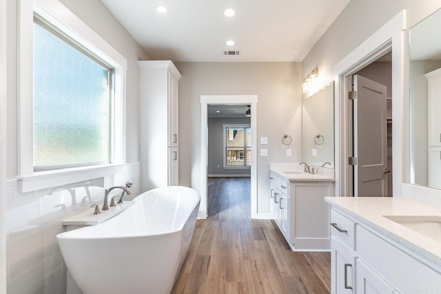 bathroom with a tub, a wealth of natural light, and wood-type flooring