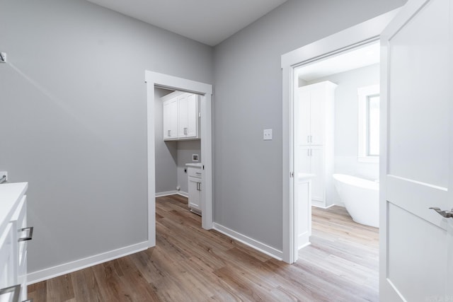 interior space featuring vanity, a bath, and hardwood / wood-style flooring