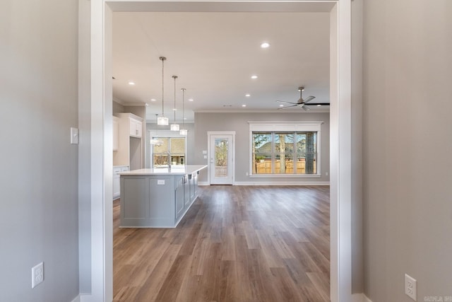 kitchen featuring white cabinetry, a center island, ceiling fan, decorative light fixtures, and ornamental molding