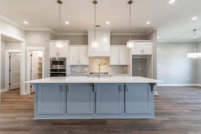 kitchen featuring decorative light fixtures, white cabinetry, dark wood-type flooring, and a large island with sink