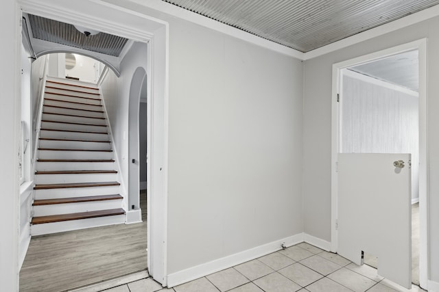 stairs with tile patterned floors and crown molding