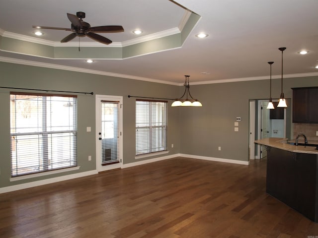 kitchen featuring ornamental molding, a raised ceiling, ceiling fan, decorative light fixtures, and dark hardwood / wood-style floors