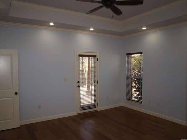 unfurnished room featuring ceiling fan, a raised ceiling, crown molding, and dark wood-type flooring