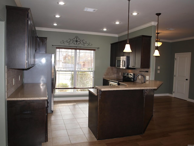 kitchen featuring kitchen peninsula, crown molding, hanging light fixtures, and stainless steel appliances