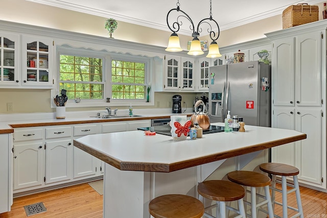 kitchen featuring sink, hanging light fixtures, a kitchen island, stainless steel fridge with ice dispenser, and white cabinets