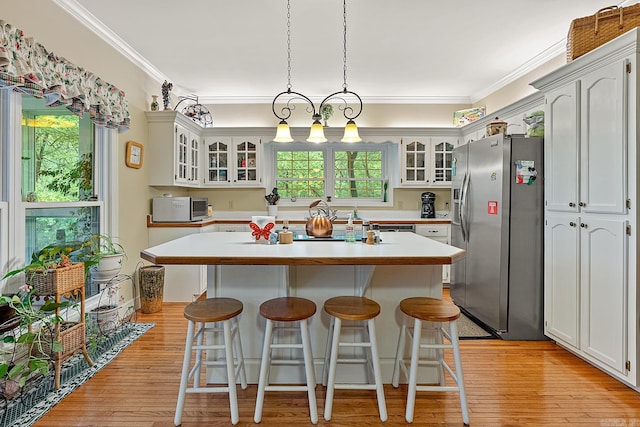 kitchen featuring white cabinets, stainless steel refrigerator with ice dispenser, and ornamental molding