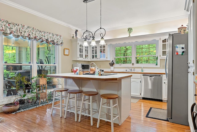 kitchen with white cabinetry, light hardwood / wood-style flooring, ornamental molding, and appliances with stainless steel finishes