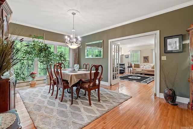 dining space with light hardwood / wood-style floors, crown molding, and an inviting chandelier