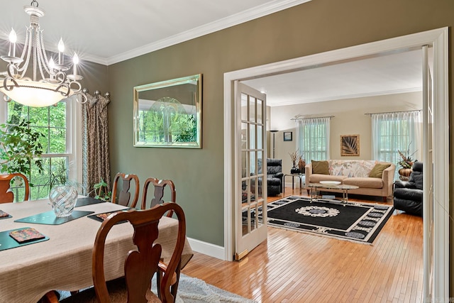 dining area with a chandelier, wood-type flooring, and ornamental molding