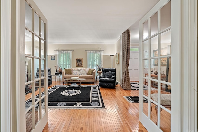 living room featuring french doors, ornamental molding, and hardwood / wood-style flooring