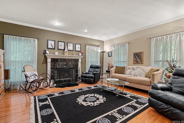 living room with hardwood / wood-style floors, crown molding, and a tile fireplace