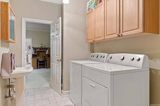 clothes washing area featuring cabinets, light carpet, washing machine and dryer, and crown molding