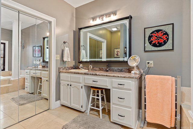 bathroom with tile patterned floors, vanity, and a relaxing tiled tub