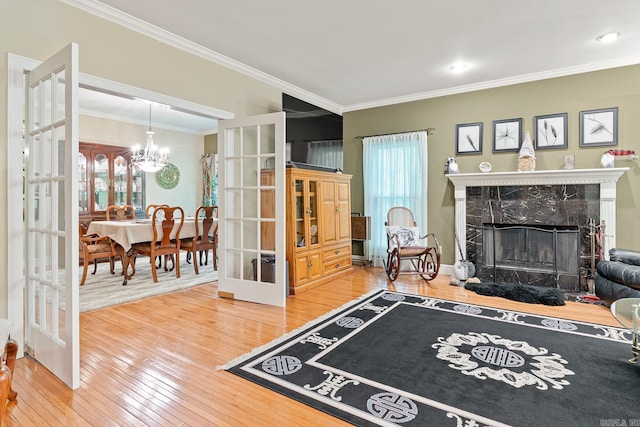 living room featuring a high end fireplace, french doors, hardwood / wood-style flooring, ornamental molding, and a chandelier