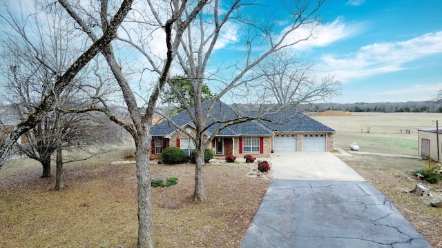 single story home with a front lawn, a rural view, and a garage