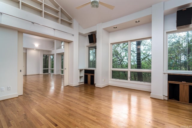 unfurnished living room featuring light wood-type flooring, a wealth of natural light, and ceiling fan