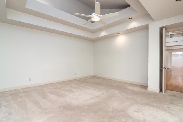 carpeted spare room with ceiling fan and a tray ceiling