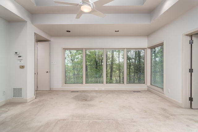 carpeted empty room with a raised ceiling and ceiling fan