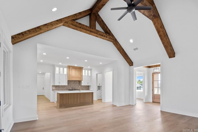 unfurnished living room featuring beam ceiling, high vaulted ceiling, light hardwood / wood-style flooring, and ceiling fan