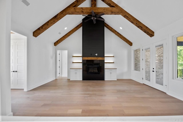 unfurnished living room with beamed ceiling, ceiling fan, a large fireplace, and french doors