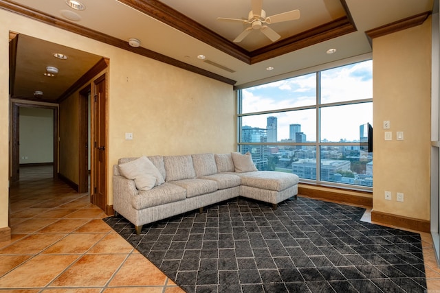 living room featuring crown molding, a tray ceiling, tile patterned floors, and ceiling fan