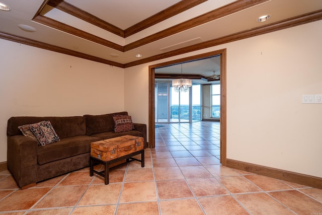 living room featuring tile patterned flooring, ornamental molding, a notable chandelier, and a tray ceiling