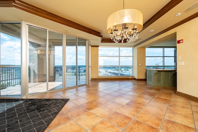 interior space featuring a raised ceiling, crown molding, a wealth of natural light, and a chandelier