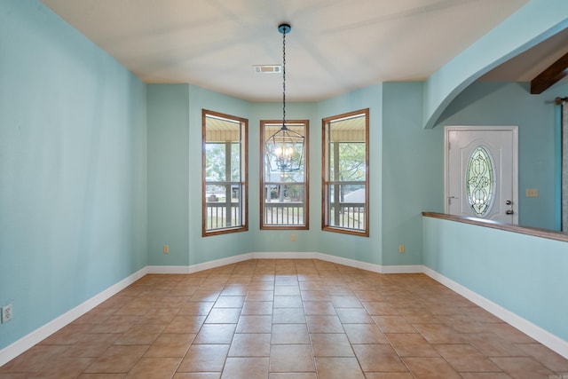 tiled empty room with a chandelier