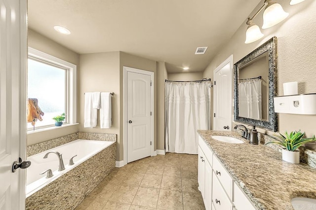 bathroom with tile patterned flooring, vanity, and tiled bath