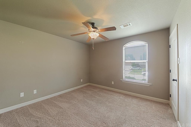 spare room with light carpet, ceiling fan, and a textured ceiling