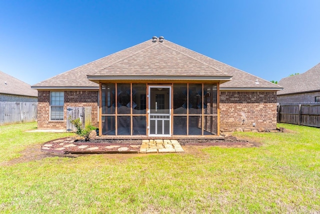 back of property with a sunroom and a yard