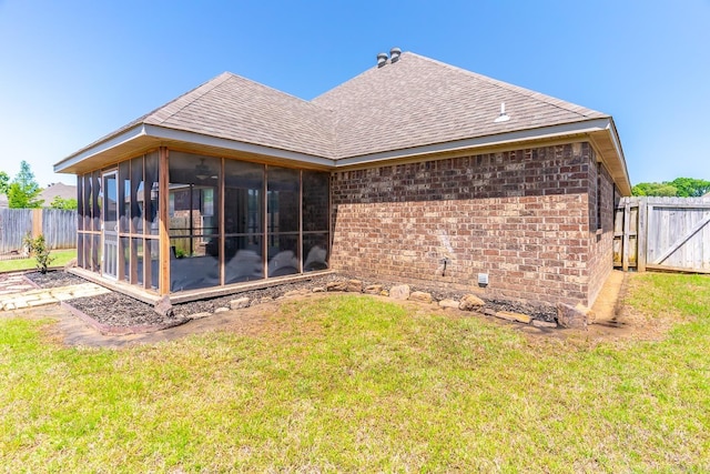 rear view of house featuring a lawn and a sunroom