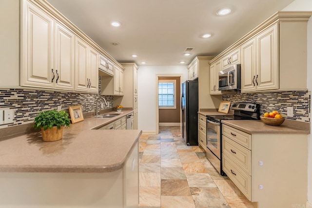 kitchen featuring kitchen peninsula, sink, stainless steel appliances, and cream cabinetry