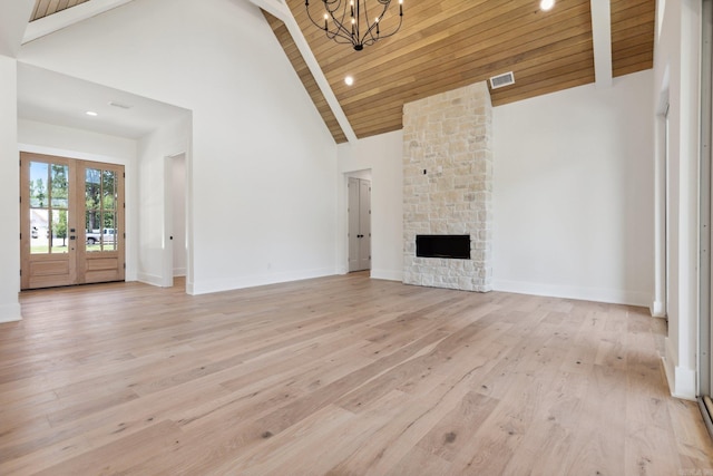 unfurnished living room featuring french doors, wooden ceiling, a stone fireplace, high vaulted ceiling, and light wood-type flooring